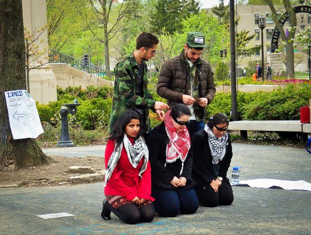 Students participate in a mock Israeli checkpoint stop near The Rock on Tuesday. Students for Justice in Palestine and MEChA de Northwestern organized the demonstration.