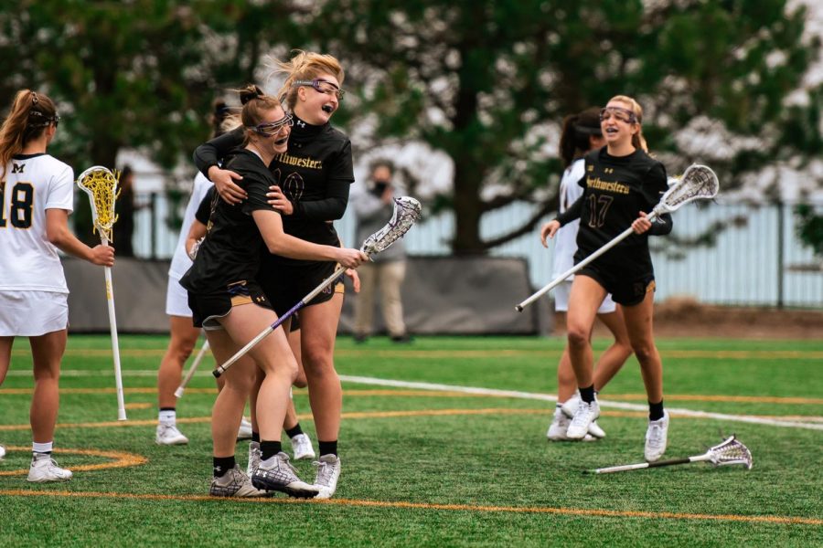 Izzy Scane (left) and Dylan Amonte hug while celebrating a goal, with Taylor Pinzone running toward them.