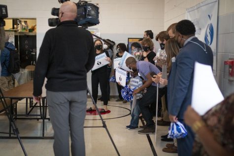A crowd of people. Meghan Rice’s husband and son are crouching down, framed by a journalist and those waiting to congratulate Meghan Rice.