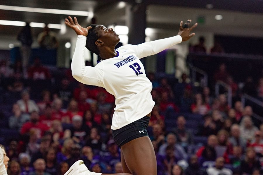 Girl with short hair in white uniform jumps to hit ball