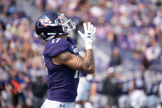 A receiver in a purple has his hand.s ready to catch a ball