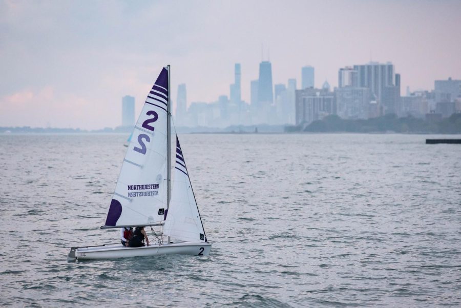 A single sailboat with the Northwestern logo floats on Lake Michigan.