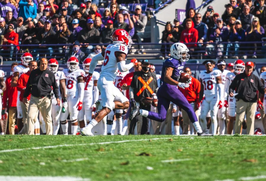 Player in purple uniform runs with football.