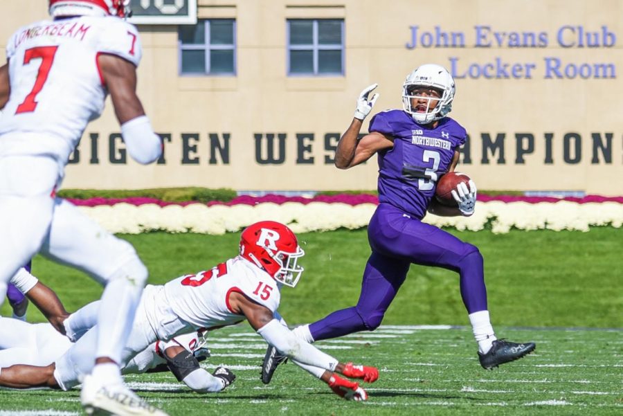 Player in purple uniform runs with football.