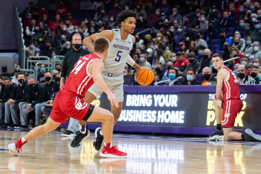 Player in gray and purple jersey readies to dribble the ball.