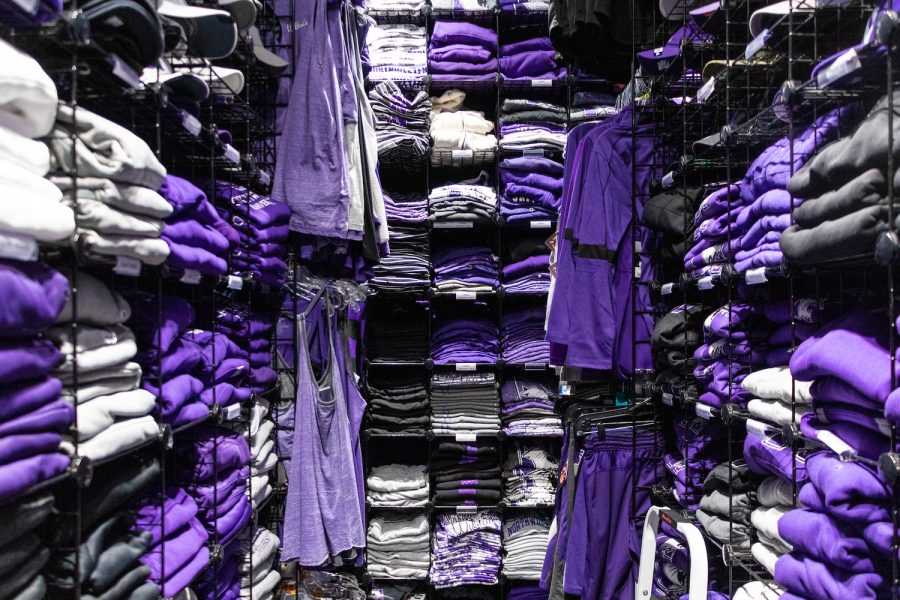 Stacks of purple clothing sit on shelves in a clothing store.