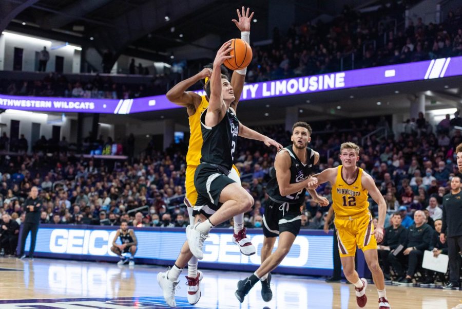 A man in a black jersey shoots a layup. 