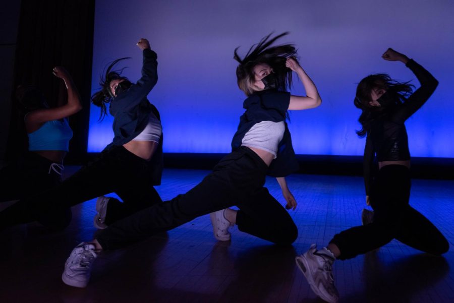 A group of dancers raise one arm and kneel on one leg while extending the other.