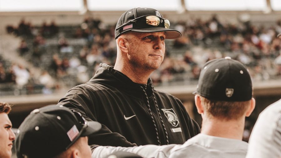 A man wearing a black hoodie with the Army West Point logo on it, a black baseball cap and sunglasses.