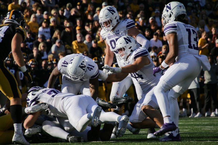 Players in white uniforms dive to tackle an opponent.