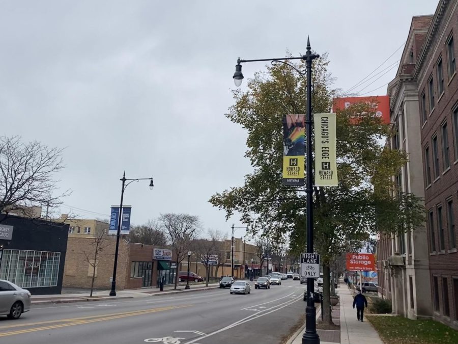 A street with gray skies. There are shops and street lights on two sides and different banners on the two sides of the road.