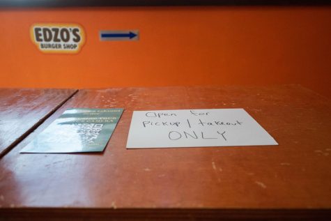 A paper sign says “Open for pickup/takeout only” next to a QR code.