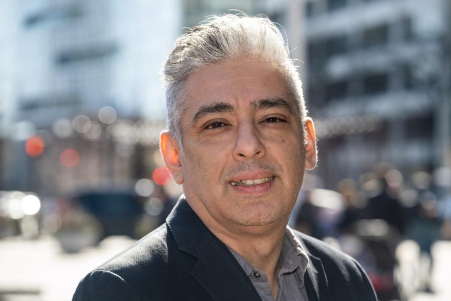 A man in a suit jacket looks at the camera, outside on a cold day.