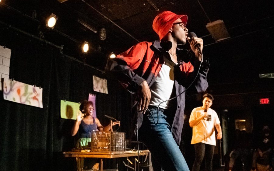 Man dances while singing into a microphone with a DJ in the background.
