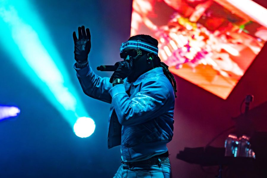 A performer waves and holds a microphone to their mouth.