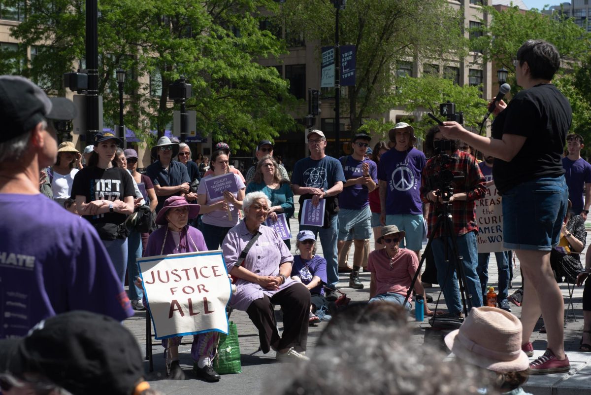 People gather holding signs to listen to a speaker.