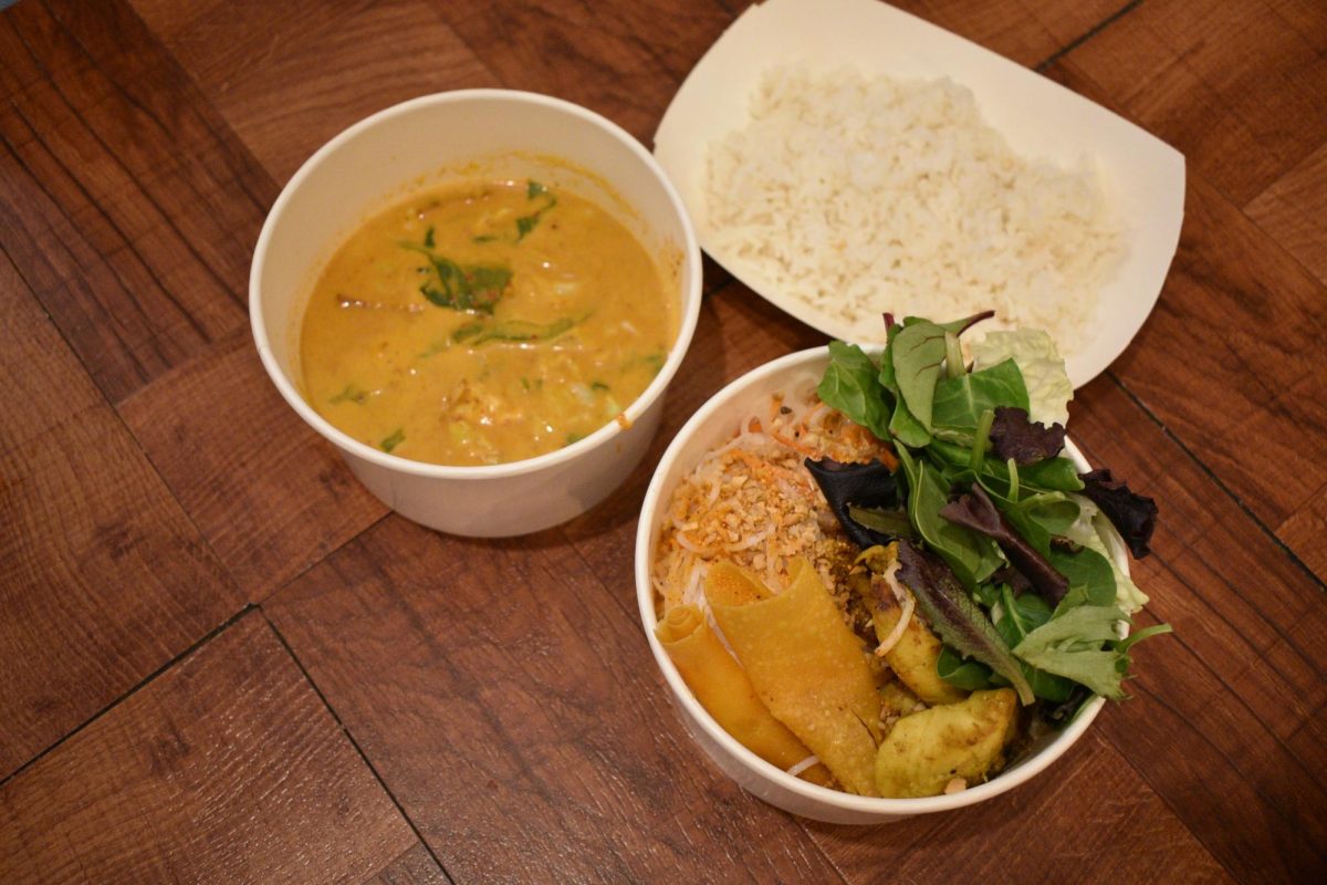 Panang curry in a white bowl, rice bowl, and rectangular plate of rice on a wooden table.