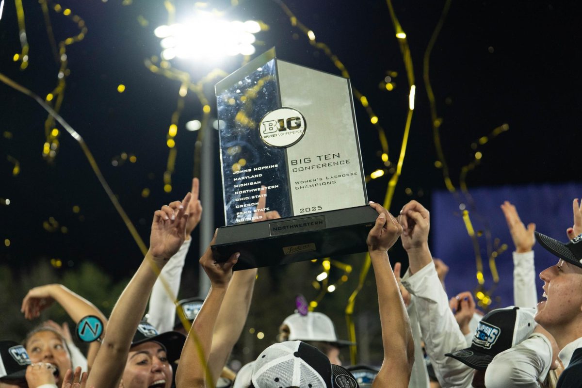 B1G Ten trophy is held above players’ heads with streamers falling in the background.