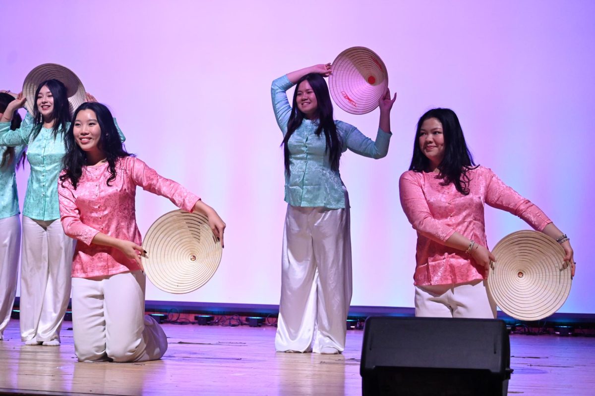Four dancers with traditional hats perform on stage.