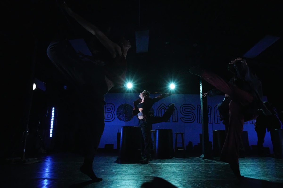 A person kicks their leg back while lights shine behind them. 