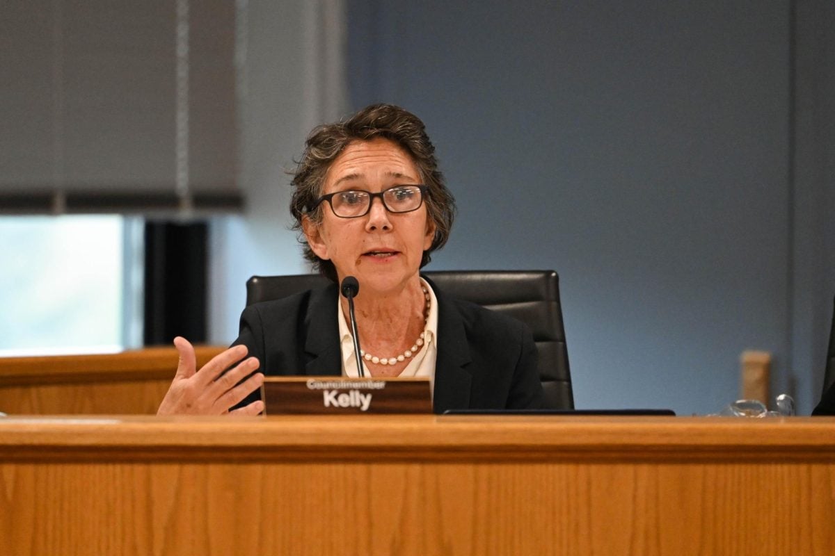 A woman speaks into a microphone at a dais.