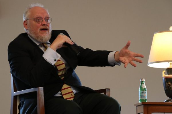 A man holds a microphone and gestures with his other hand.