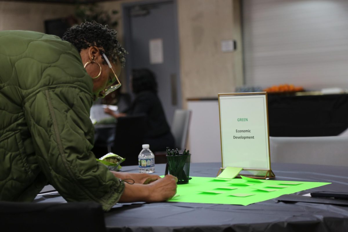 A woman writes on a green poster.