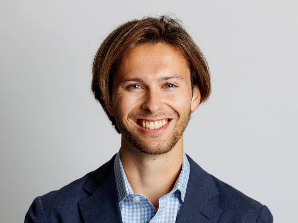 A headshot of Tyler Smith wearing a navy blue suit.