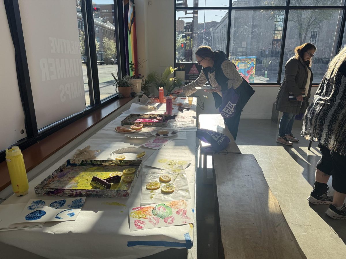 A woman leans over a table with paint and fruit.
