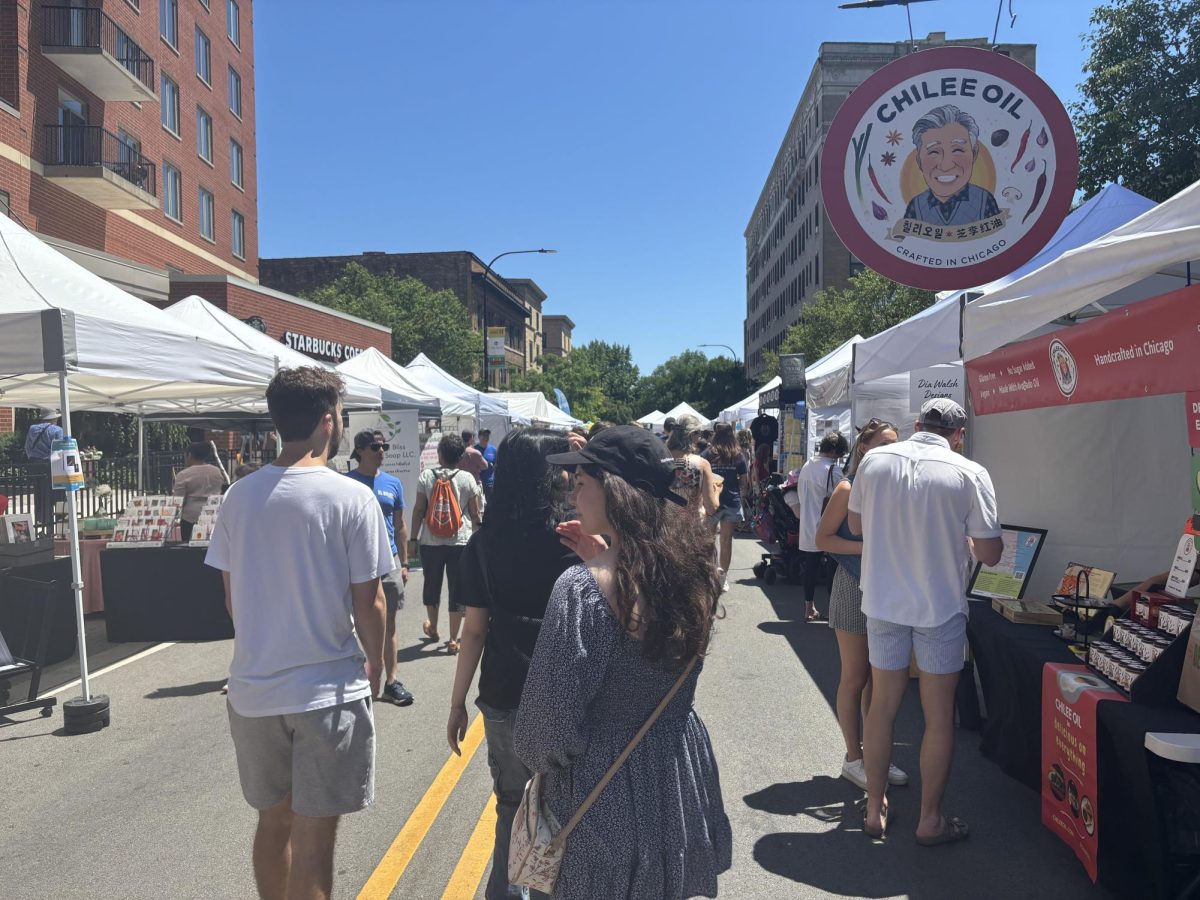 Crowds of people in front of two parallel rows of white vendor tents.
